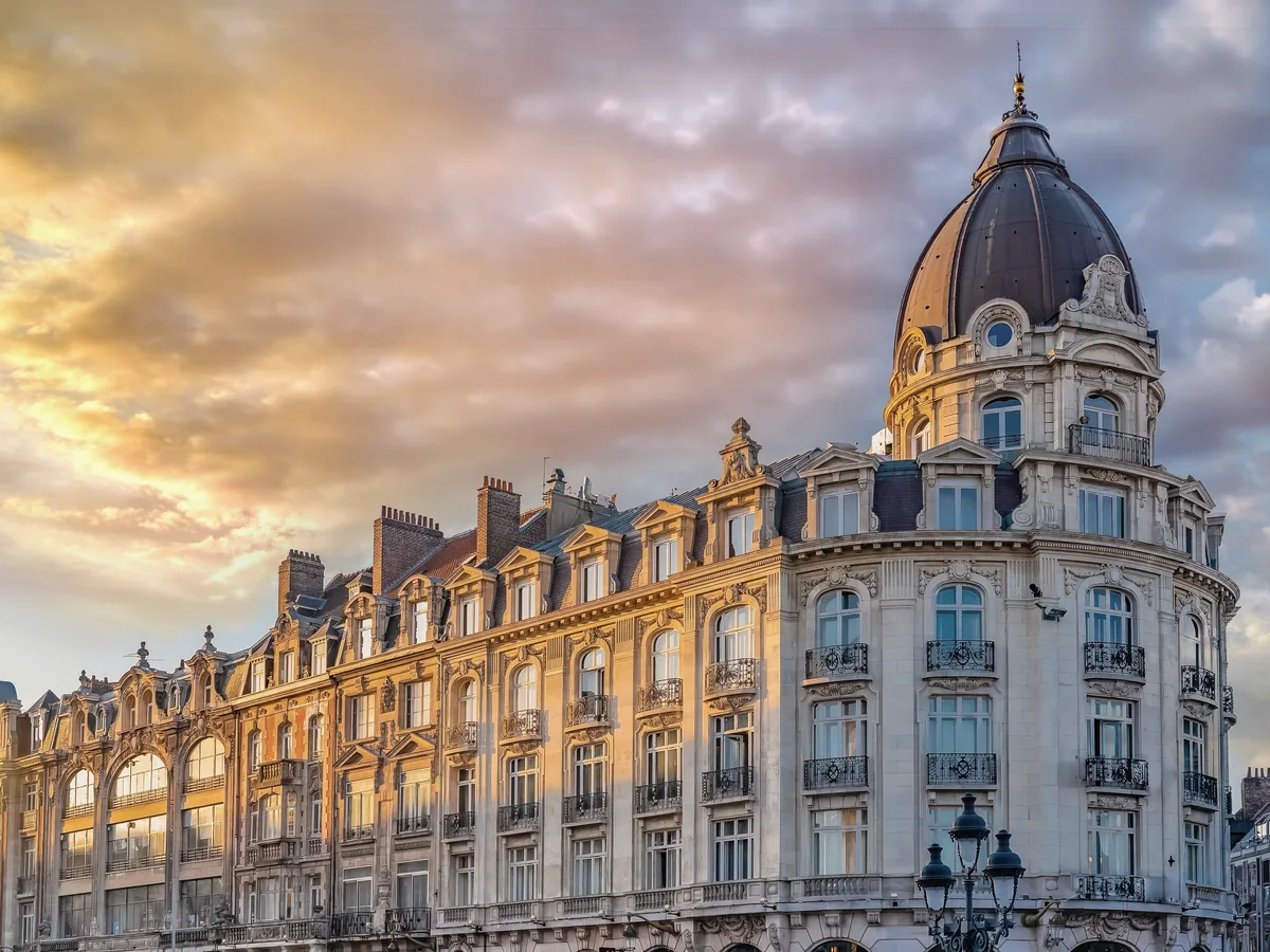 Immeuble de style haussmannien surmonté d’une coupole, au coucher du soleil